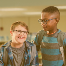 A Causasian boy with disabilities and a Black American boy stand together.
