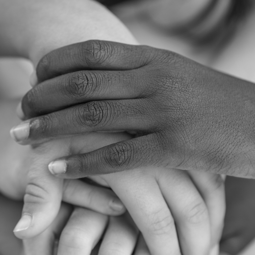 Children layer their hands together on a table. Click to access the Racial Equity resource guide.
