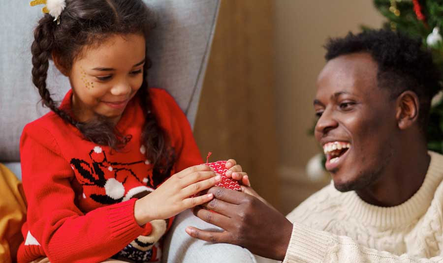 A Black American father and daughter exchange gifts.