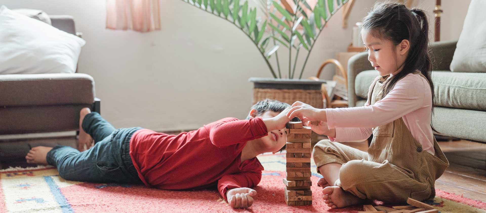 Two children - a boy and a girl - stacking a tower of blocks.